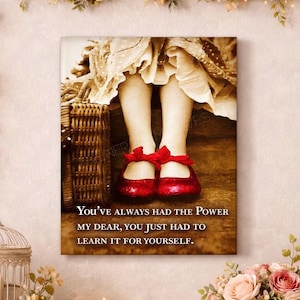 May include: A sepia-toned canvas print showing a child's legs and red glitter shoes with bows. A woven basket is on the left. The text reads: "You've always had the power my dear, you just had to learn it for yourself."