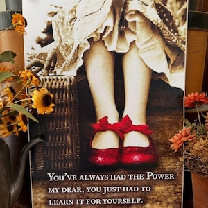 Puede incluir: Una imagen de inspiración vintage de una niña con zapatos rojos con una cita que dice "You've always had the power my dear, you just had to learn it for yourself."
