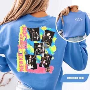 Puede incluir: Una sudadera de cuello redondo color azul Carolina con un gráfico en la espalda que incluye el texto NEW KIDS ON THE BLOCK y cuatro fotos en blanco y negro de los miembros de la banda. El pecho muestra el texto NKOTB EST 1986 en blanco.