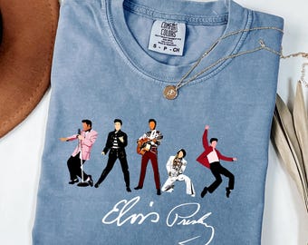 Könnte beinhalten: Ein kurzärmeliges T-Shirt in Jeansblau mit fünf grafischen Illustrationen von Elvis Presley in verschiedenen Posen und Outfits, wobei die Signatur Elvis Presley in weißer Schreibschrift unter den Figuren steht und ein Comfort Colors Etikett.