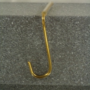 Può includere: Un gancio per calze in metallo dorato a forma di J.