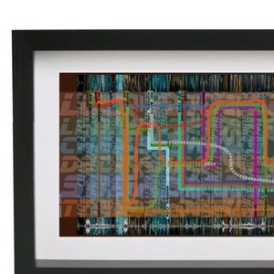 Op de afbeelding: Een ingelijste abstracte kunstprint met een kleurrijk, gelaagd ontwerp met lijnen en vormen. De print is geplaatst tegen een achtergrond van gedempte blauwe en grijze tinten.