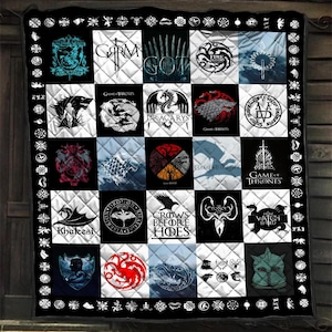 May include: A quilted throw blanket featuring a grid of various Game of Thrones themed graphics, including house sigils, dragons, the Iron Throne, and text such as Dracarys, Khaleesi, and Crows Before Hoes, all framed by a black border with white icons.