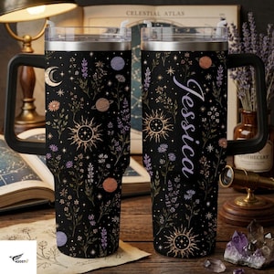 May include: A black stainless steel tumbler with a handle and clear lid, featuring a celestial pattern of suns, moons, planets, and wildflowers. The right side of the tumbler displays the name Jessica in a white cursive script font.