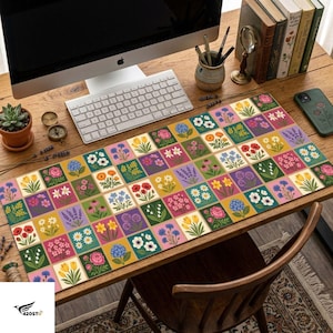 May include: A rectangular desk mat featuring a grid pattern of colorful square illustrations of various flowers including tulips, poppies, daisies, and lavender on a wooden desk with a computer monitor, keyboard, and books.