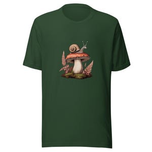 May include: A dark forest green short-sleeve t-shirt featuring a central graphic print of a snail resting on top of a large, reddish-brown mushroom cap, surrounded by small green mossy patches and delicate, light brown fern-like foliage.