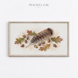 May include: A framed horizontal print featuring a watercolor illustration of a striped brown feather surrounded by several small brown acorns and green and orange oak leaves. The text PEACEFUL OAK PRINTS is centered above the artwork.