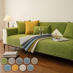 May include: A green textured sofa cover draped over a couch with a yellow square pillow and a green rectangular pillow. A stack of folded fabric swatches in various colors sits below, alongside a color palette of ten circular fabric samples.