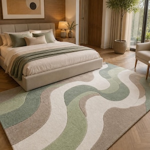 May include: A rectangular area rug featuring a wavy, abstract pattern in shades of sage green, cream, and beige. The design consists of flowing, curved bands of varying widths that create a rhythmic, organic movement across the entire surface.