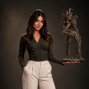 May include: A detailed collectible figurine depicting two small figures standing atop a large, textured, tree-like creature with bark-like skin and branch-like limbs, mounted on a dark, circular base with a rocky, uneven surface texture.