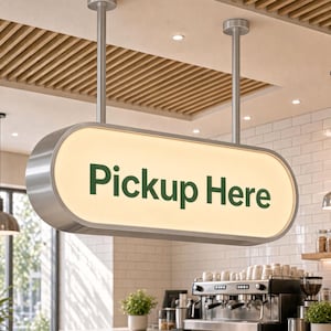 May include: A horizontal oval-shaped hanging sign with a brushed metal frame and an illuminated white face. The text "Pickup Here" is printed in dark green sans-serif letters on the center of the sign, which is suspended by two metal poles.