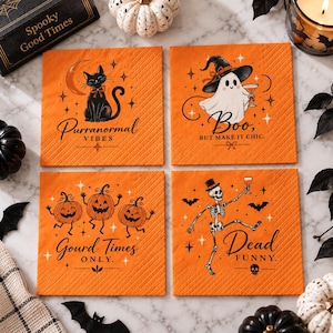 May include: Four square orange paper napkins featuring Halloween illustrations. One shows a black cat with the text Purranormal Vibes, one a ghost with Boo, but make it chic, one three pumpkins with Gourd Times Only, and one a skeleton with Dead Funny.