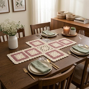 May include: A rectangular crochet table runner featuring a central cream-colored square surrounded by four smaller cream and dusty rose squares. The runner has a scalloped edge and is laid across a dark wood dining table with place settings.
