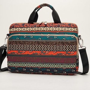 Könnte beinhalten: Eine rechteckige Laptoptasche mit einem mehrfarbigen horizontalen Streifenmuster, das florale und geometrische Motive in Orange-, Petrol-, Braun- und Dunkelblautönen aufweist. Sie verfügt über zwei schwarze Tragegriffe, einen abnehmbaren Schultergurt und Reißverschlüsse.