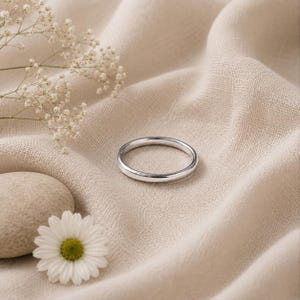 Könnte beinhalten: Ein schlichter, polierter Ring in Silberoptik mit einer glatten, abgerundeten Oberfläche. Der Ring zeichnet sich durch ein klassisches, minimalistisches kreisförmiges Design mit einer reflektierenden Metalloberfläche aus.