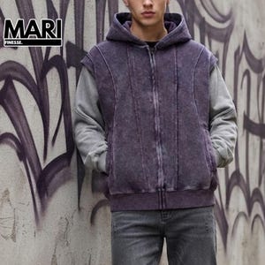 Pode incluir: Um casaco com capuz e fecho de correr, apresentando um colete sem mangas roxo escuro com efeito lavado sobre mangas compridas cinzentas. A peça inclui capuz, fecho frontal completo e detalhes de costura vertical. Texto MARI FINESSE visível.