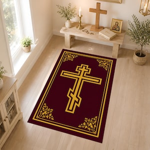 Könnte beinhalten: Ein rechteckiger Teppich mit einem tief burgunderroten Hintergrund und einem markanten, goldfarbenen orthodoxen Kreuz in der Mitte. Der Teppich ist von einem goldenen Rand mit komplizierten floralen Rankenmustern in allen vier Ecken umrahmt.