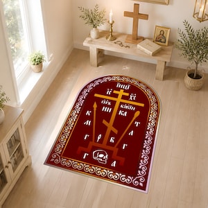 Könnte beinhalten: Ein bogenförmiger Teppich mit tiefrotem Hintergrund, einem goldfarbenen orthodoxen Kreuz, einem Totenkopf an der Basis und verschiedenen kyrillischen Schriftzeichen. Der Teppich ist von einem dekorativen weiß-roten Rankenmuster umrandet.