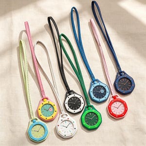 May include: A collection of eight octagonal pendant watches, each featuring a matching long strap. The watches come in various colours including light green, pink, white, black, dark green, light blue, and dark blue, with textured dials.