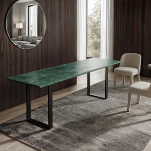 May include: A rectangular dining table featuring a green marble top with natural veining and a black metal frame with two U-shaped legs. The table is accompanied by two beige upholstered chairs with rounded backs and short, sturdy legs.