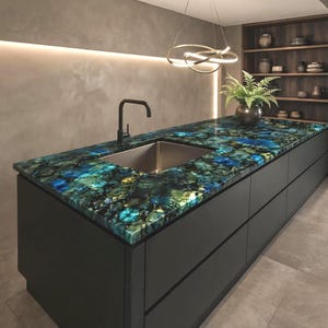 May include: A kitchen island featuring a polished blue and green gemstone countertop with a rectangular stainless steel sink and a matte black faucet. The base of the island consists of dark gray flat-panel cabinetry with horizontal drawer pulls.