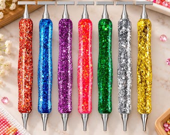 Könnte beinhalten: Ein Set aus sieben Diamond-Painting-Stiften mit glitzernden, durchscheinenden Griffen in Rot, Blau, Lila, Pink, Grün, Silber und Gold. Jeder Stift hat ein metallisches T-förmiges Ende und eine spitze Metallspitze zum Setzen der Steine.