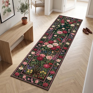 Op de afbeelding: Een lange rechthoekige loper met een donkergroene achtergrond en een gedetailleerd botanisch patroon van rode, roze en witte rozen, kleine gele bloemen, paarse bloesems, groen blad, vlinders en kleine vogels verspreid over het ontwerp.