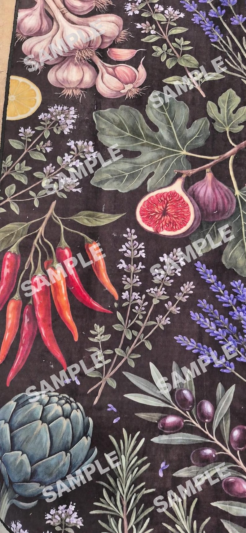 Op de afbeelding: Een donkerbruine stof met een botanische print van knoflookbollen, een schijfje citroen, vijgen en bladeren, rode chilipepers, lavendeltakjes, een artisjok en donkerpaarse olijven met groene bladeren verspreid over het oppervlak.