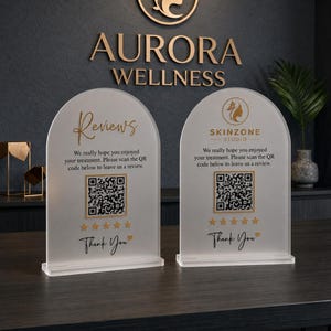 May include: Two arched, frosted acrylic signs with gold text and accents. The left sign reads Reviews, and the right sign features the Skinzone Studio logo. Both include a QR code, five gold stars, and the text Thank You with a small heart.