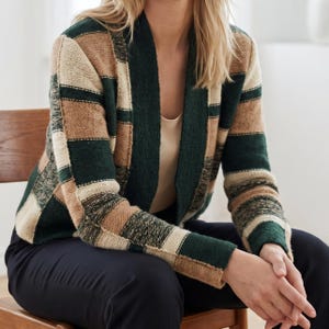 May include: A long-sleeve open-front cardigan featuring a block-patterned knit design in alternating shades of forest green, tan, and cream. The garment has a solid dark green ribbed collar and cuffs, with a textured knit finish throughout the body.