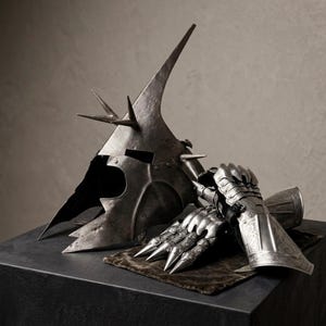 May include: A dark, weathered metal helmet featuring a tall, pointed crown and multiple spikes, paired with a polished steel gauntlet that has articulated finger plates and intricate etched detailing on the wrist and forearm sections.
