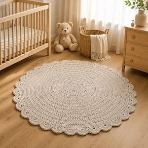 Peut inclure: Un tapis rond en crochet de couleur crème présentant un motif circulaire texturé qui rayonne du centre vers l'extérieur, fini avec un bord festonné décoratif. Le tapis est fabriqué avec du fil épais, créant un revêtement de sol dense.