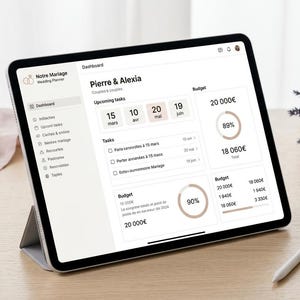 May include: A tablet displaying a wedding planner dashboard titled Notre Mariage with the names Pierre & Alexia, showing upcoming tasks, budget progress circles, and financial data in Euros, with a stylus resting on the surface nearby.