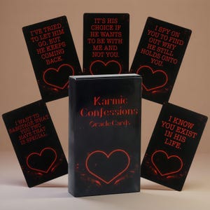 May include: A deck of Karmic Confessions oracle cards in a black box with red text and a heart icon. Five individual cards are fanned out behind the box, each featuring black backgrounds, red text with relationship-themed confessions, and a red heart.