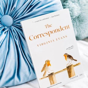 May include: A book titled The Correspondent by Virginia Evans with a white cover featuring two robins perched on wooden posts. The text includes the quote ...a cause for celebration... by Ann Patchett and the words A Novel printed on the front.