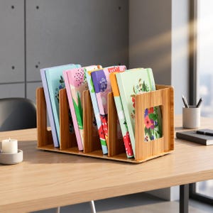 以下が含まれることがあります： 5つの垂直スロットを備えた木製のデスクトップオーガナイザーで、複数のノートが収納されています。ノートの表紙は、花柄、フルーツ柄、抽象的な模様など、カラフルなデザインです。オーガナイザーは明るい木目調の仕上げで、側面に四角い切り抜きがあります。