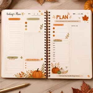 Può includere: Un'agenda a spirale aperta con pagine color crema caratterizzate da illustrazioni autunnali di zucche e foglie d'acero. Il layout include sezioni per piani giornalieri, priorità, gratitudine e programmi con testo stampato.