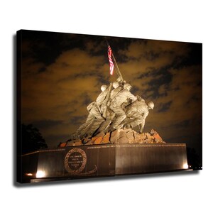 May include: A canvas print of the United States Marine Corps War Memorial at night, featuring bronze figures raising an American flag. The black granite base displays the text 'UNCOMMON VALOR WAS A COMMON VIRTUE' within a circular laurel wreath.