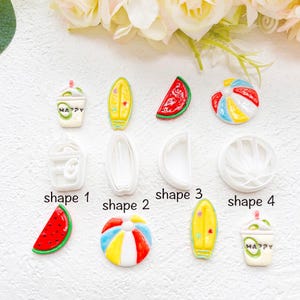 May include: A collection of summer-themed resin charms and white plastic cutters featuring a drink cup with the text HAPPY, a surfboard, a watermelon slice, and a beach ball. The set includes four distinct shapes labeled shape 1 through 4.