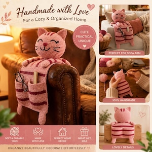 Op de afbeelding: Een roze en donkerroze gestreepte gehaakte kattenorganizer met een kattenkop, twee voorzakken en bungelende pootjes. De organizer is ontworpen om over een bankleuning te hangen en bevat de tekst Handmade with Love, For a Cozy & Organized Home.