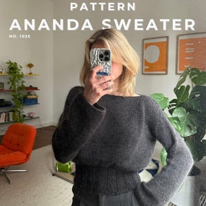 Könnte beinhalten: Ein dunkelgrauer Langarmpullover mit breitem Rippstrickbund und U-Boot-Ausschnitt. Der Text PATTERN ANANDA SWEATER NO. 1025 ist in Weiß am oberen Bildrand zu sehen.