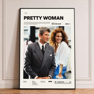 May include: A framed movie poster for Pretty Woman featuring a photograph of a man in a grey suit and a woman in a white shirt and blue skirt. The poster includes the title, director Garry Marshall, a brief synopsis, and cast information.