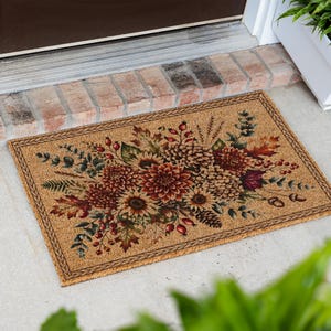 May include: A rectangular coir doormat featuring a printed autumn-themed design. The center displays a vibrant arrangement of dark red dahlias, sunflowers, pinecones, acorns, red berries, and various green and brown fall foliage leaves.