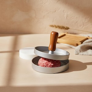 Burgerpers, aluminium burgermaker met houten handvat, hamburgervorm met burgerpapiertjes voor zelfgemaakte hamburgers, barbecue en voedselbereiding in de keuken.