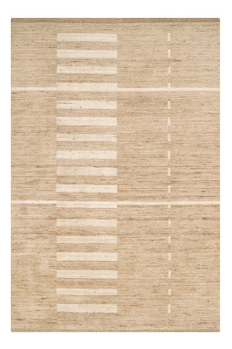 May include: A rectangular area rug featuring a woven texture in shades of tan and beige. The design consists of horizontal and vertical lines forming a grid pattern, with a prominent wide vertical band of alternating light and dark stripes.
