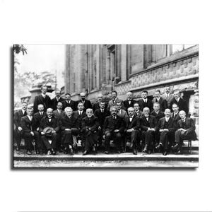 May include: A black and white historical photograph depicting a large group of scientists posing in front of a stone building. The individuals are dressed in formal suits and coats, with one woman seated in the front row among the men.