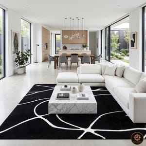 Puede incluir: Una alfombra rectangular grande con un fondo negro sólido y líneas blancas finas y fluidas que crean un patrón orgánico similar a una red en toda la superficie. La alfombra está colocada debajo de una mesa de centro de mármol blanco.