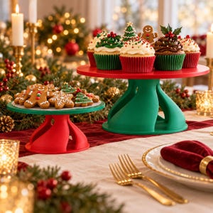 May include: Two tiered cake stands in red and green, featuring a larger green stand holding decorated cupcakes and a smaller red stand holding gingerbread cookies shaped like people, snowflakes, and Christmas trees.
