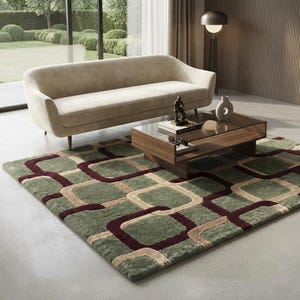 May include: A rectangular area rug featuring a repeating geometric pattern of rounded squares in shades of sage green, deep burgundy, and beige. The rug has a thick, textured pile and is positioned on a light grey floor beneath a wooden coffee table.