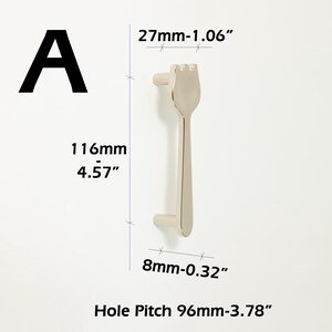 May include: A silver-toned metal cabinet handle shaped like a fork with a total length of 116mm (4.57 inches), a width of 27mm (1.06 inches), a base width of 8mm (0.32 inches), and a hole pitch measurement of 96mm (3.78 inches), labeled as A.